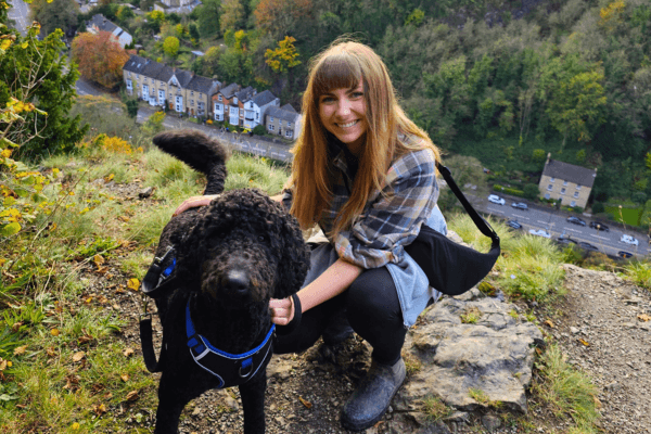A student hikes with a black dog in Autumn